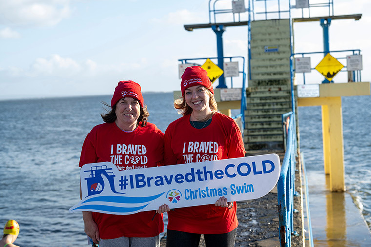 two cope galway staff holding christmas swim sign